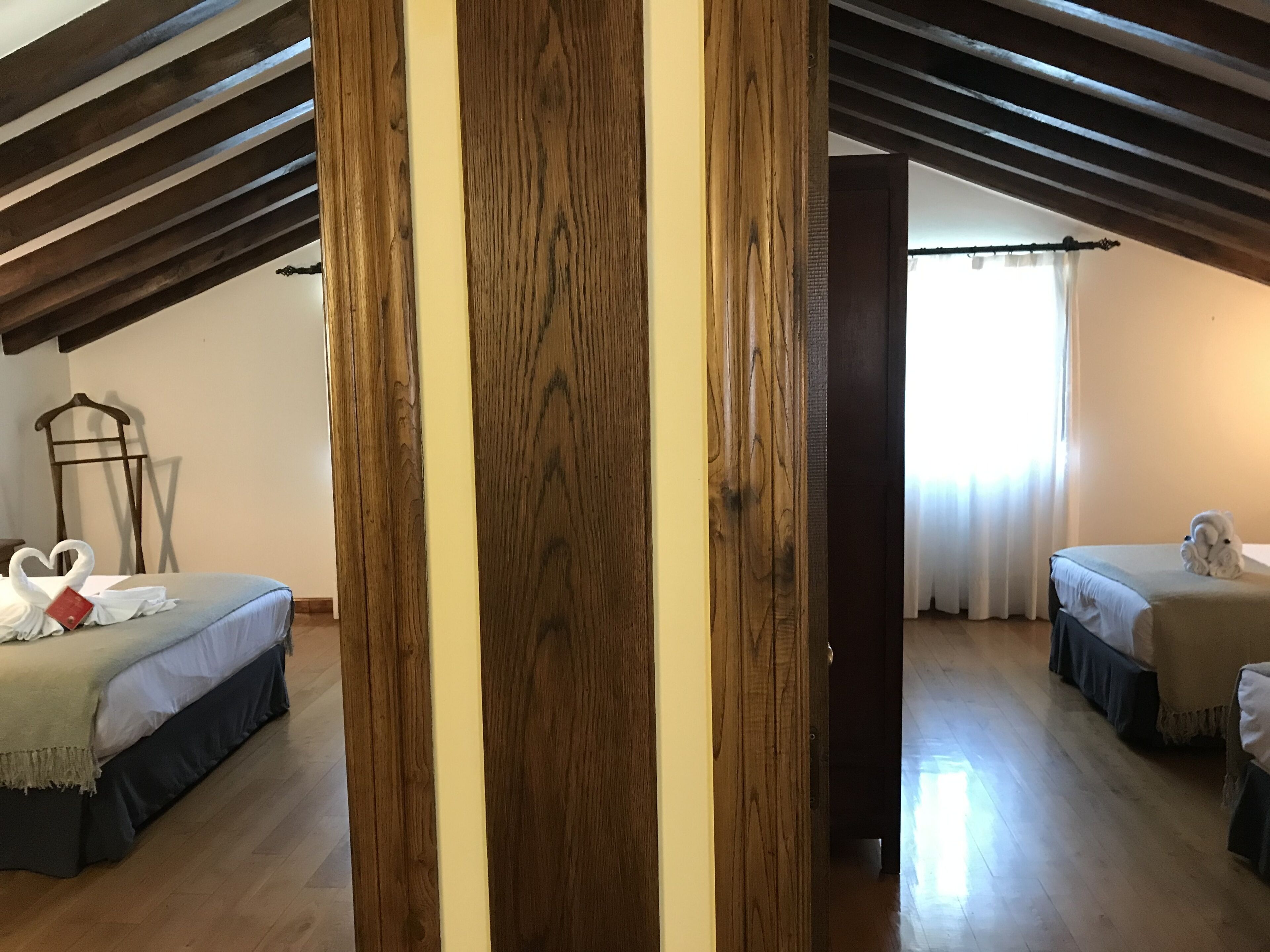 Une chambre avec deux lits, des poutres en bois au plafond et une grande porte en bois.