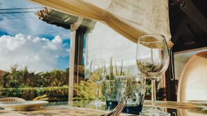 A table set with wine glasses, a fork, and a knife, with a view of greenery and a clear sky through a window. - Posada San Marcos (Santillana del Mar)