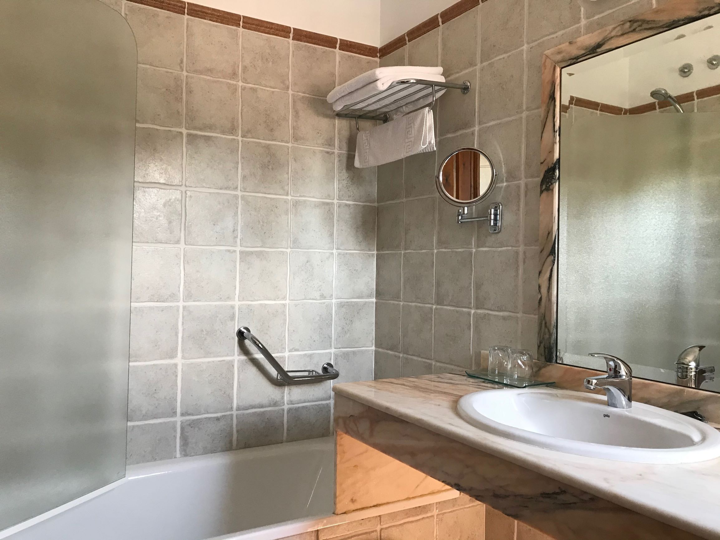 Une salle de bain équipée d’une baignoire, d’un lavabo, d’un miroir et d’un porte-serviettes.
