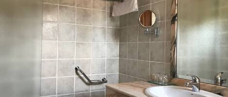 A bathroom with a bathtub, a sink, a mirror, and a towel rack.