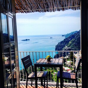 A balcony with a table and chairs overlooking a coastal view. - Bed & Breakfast Mamma Rosa (Positano)