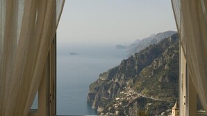 A coastal view through curtains, featuring a mountainous landscape and a body of water. - Bed & Breakfast Mamma Rosa (Positano)