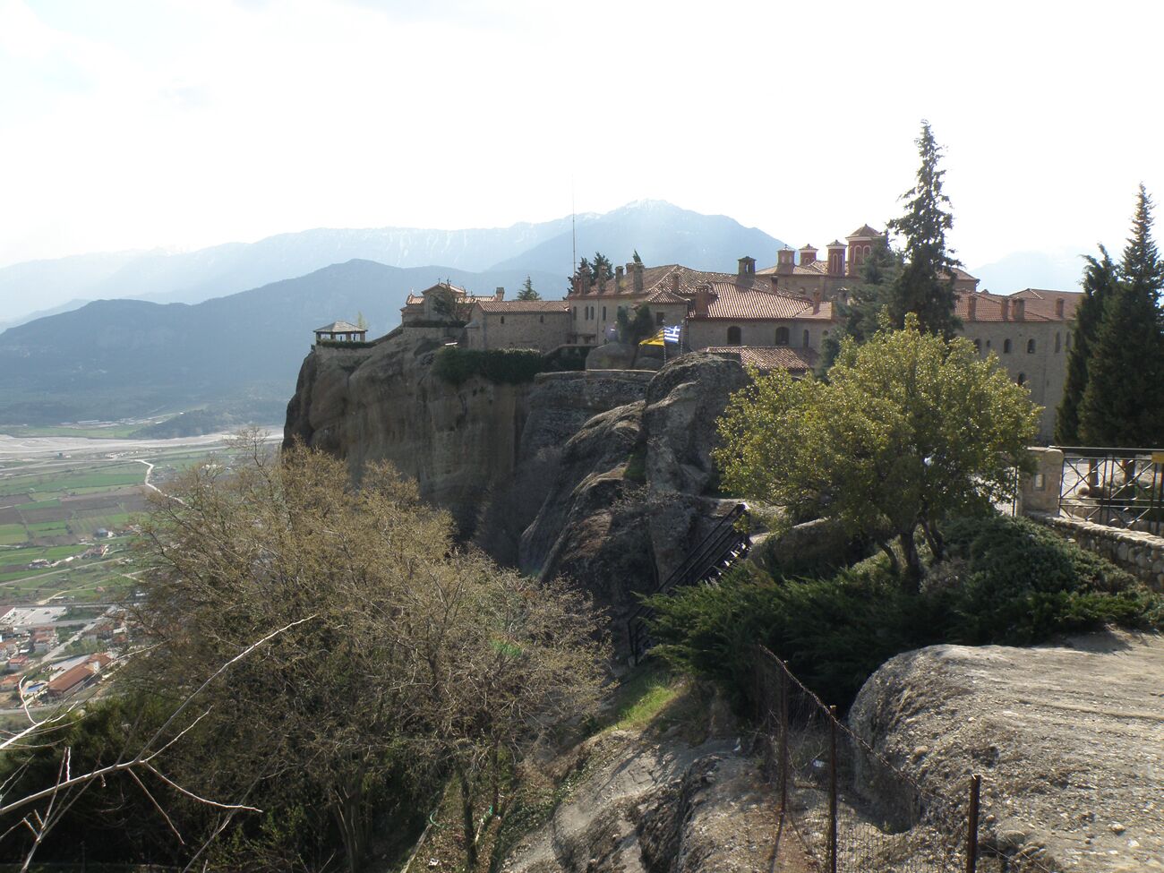 Un edificio histórico asentado en un acantilado con vistas a un valle y montañas.