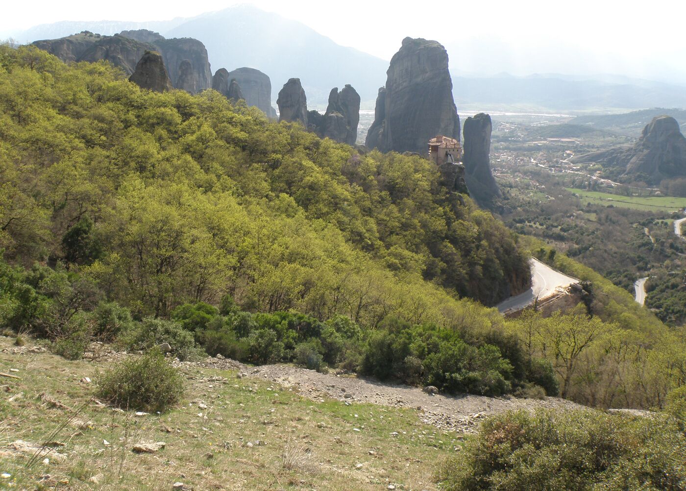 Un paisaje montañoso con formaciones rocosas destacadas y una carretera serpenteando por el valle.