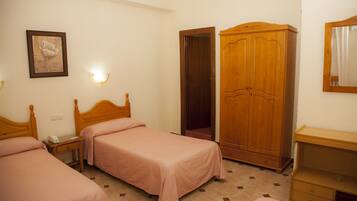 A bedroom with two single beds, a wardrobe, a bedside table with a lamp, and a framed picture on the wall.
