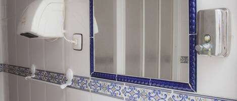 A bathroom with a white sink, a mirror with a blue frame, and a towel rack.