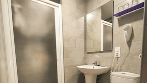 A bathroom with a toilet, sink, and a mirror above the sink. - Hostal París (La Línea de la Concepción)