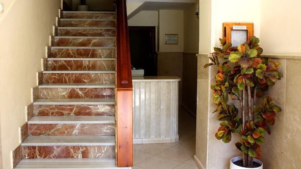 A marble staircase with a wooden handrail leading to a reception area. - Hostal París (La Línea de la Concepción)
