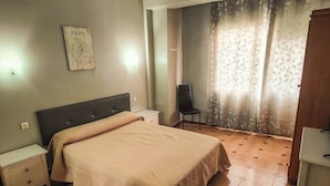A bedroom with a bed, a nightstand, a chair, a wardrobe, and a map on the wall. - Hostal París (La Línea de la Concepción)