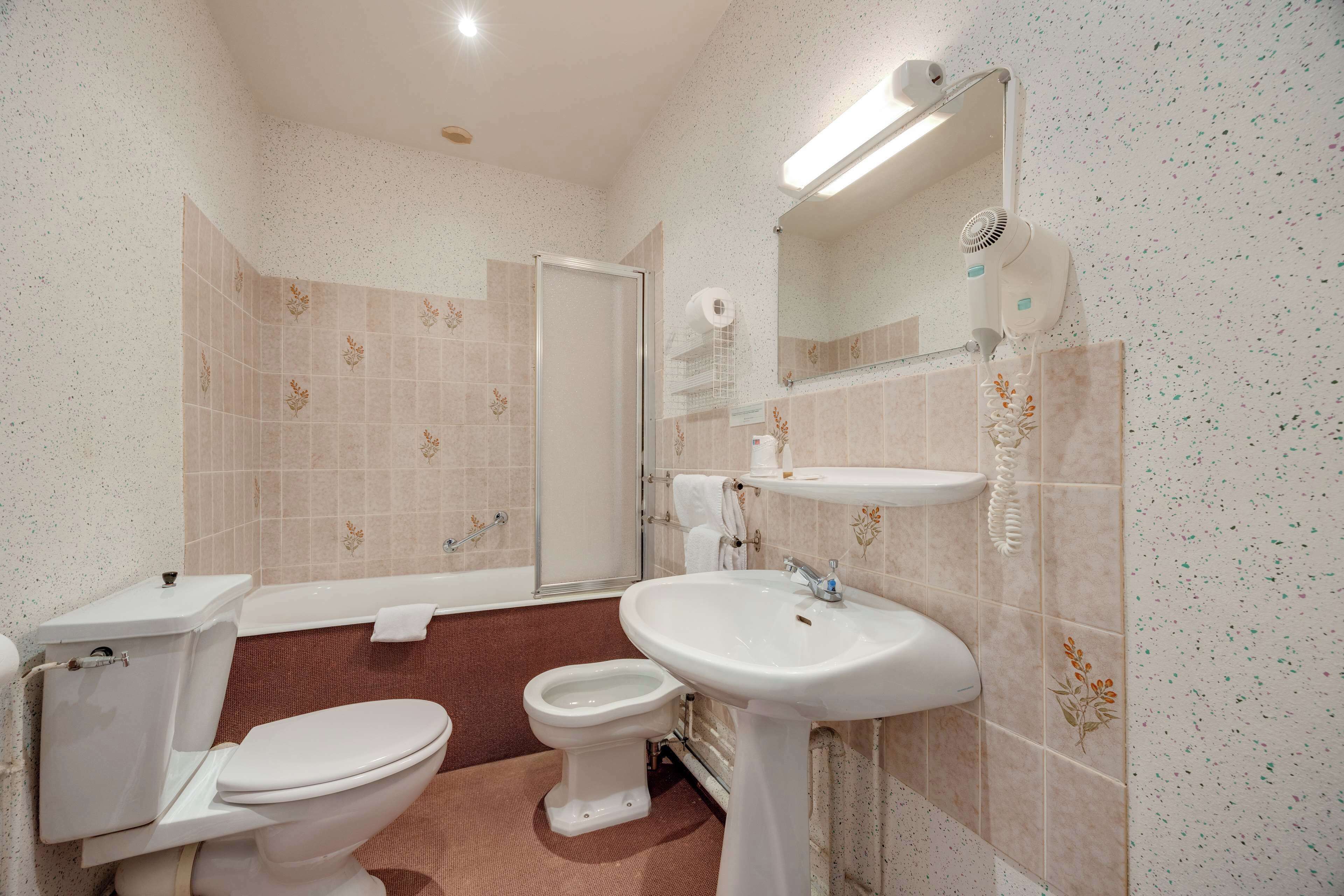Ein Badezimmer mit Toilette, Bidet, Waschbecken und Spiegel.