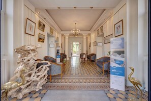 Een hotel lobby met een patroon vloer, ingelijste kunstwerken aan de muren en een receptiebalie.