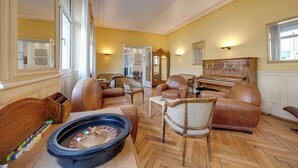 Een ruime woonkamer met een piano, leren banken en een roulette.