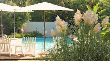 Una piscina al aire libre, sombrillas, sillones reclinables de piscina