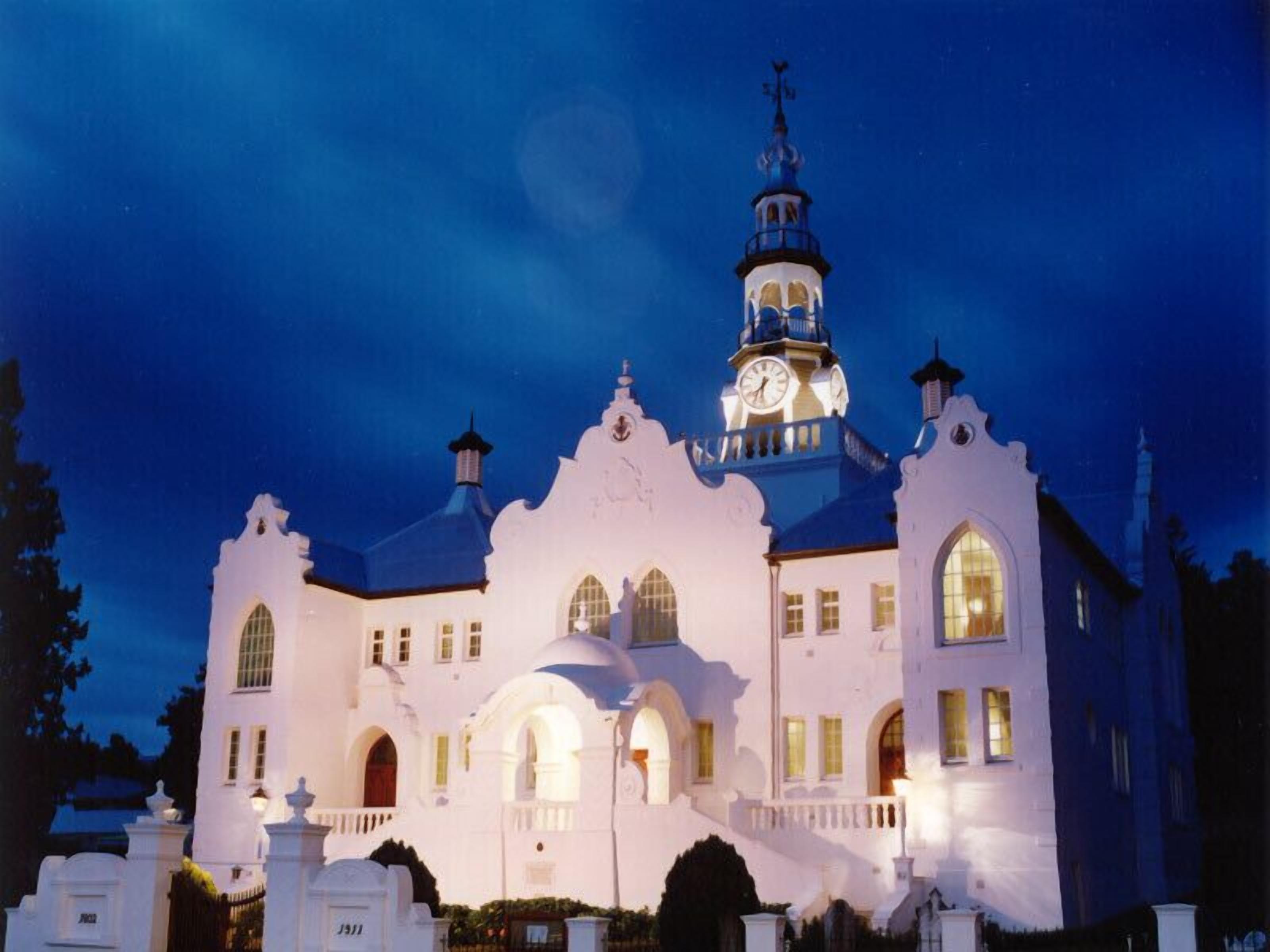A large, white building with multiple arched windows and a clock tower.