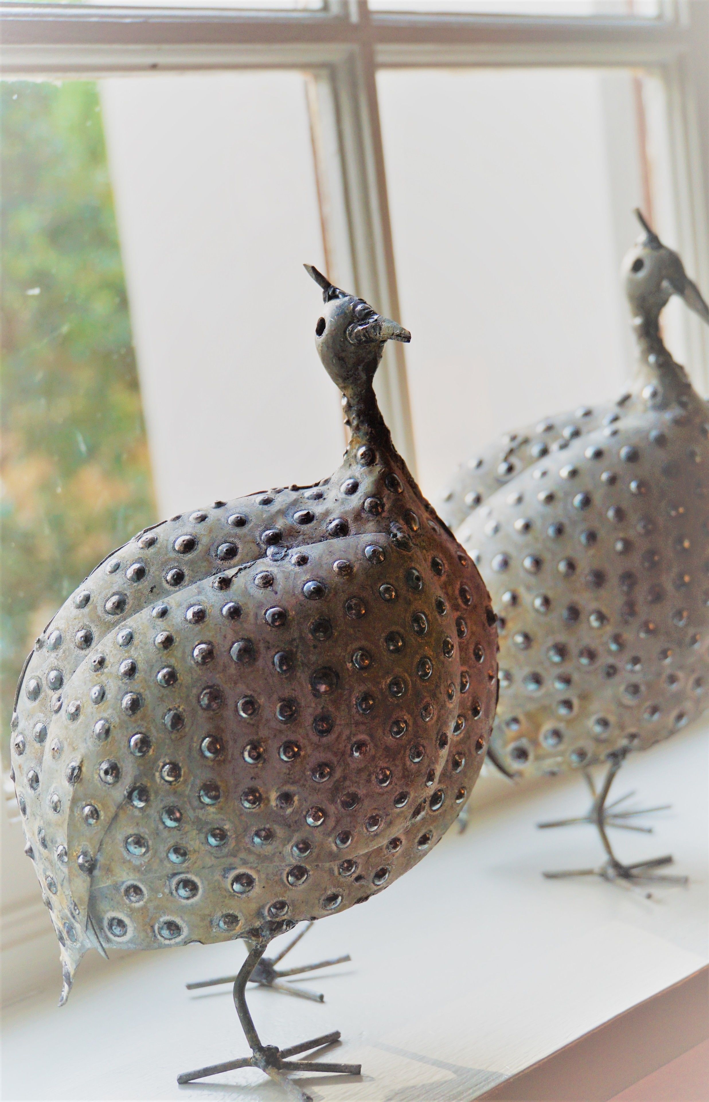Une sculpture d’oiseau posée sur un rebord de fenêtre.