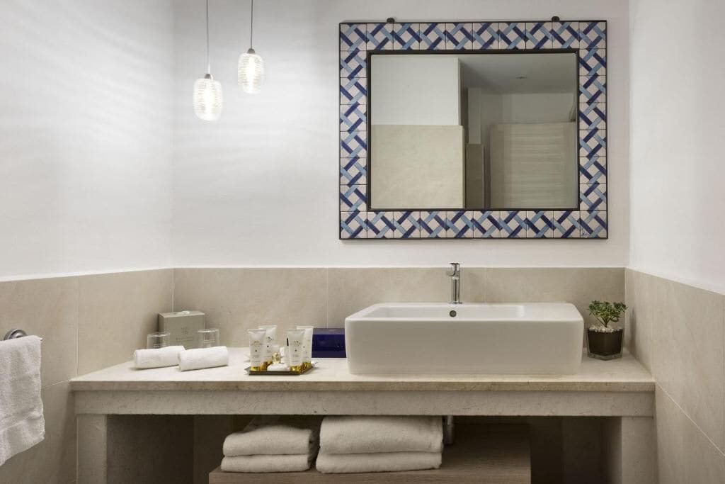 Un baño moderno con un espejo grande, una bañera y un tocador con artículos de aseo.