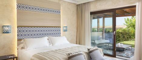 A modern hotel room with a large bed, a sofa, and a sliding glass door leading to an outdoor patio.