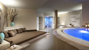 A modern spa room with a large bathtub, a seating area with a sofa, and a separate shower area. - Baglioni Resort Sardinia - The Leading Hotels of the World (San Teodoro)