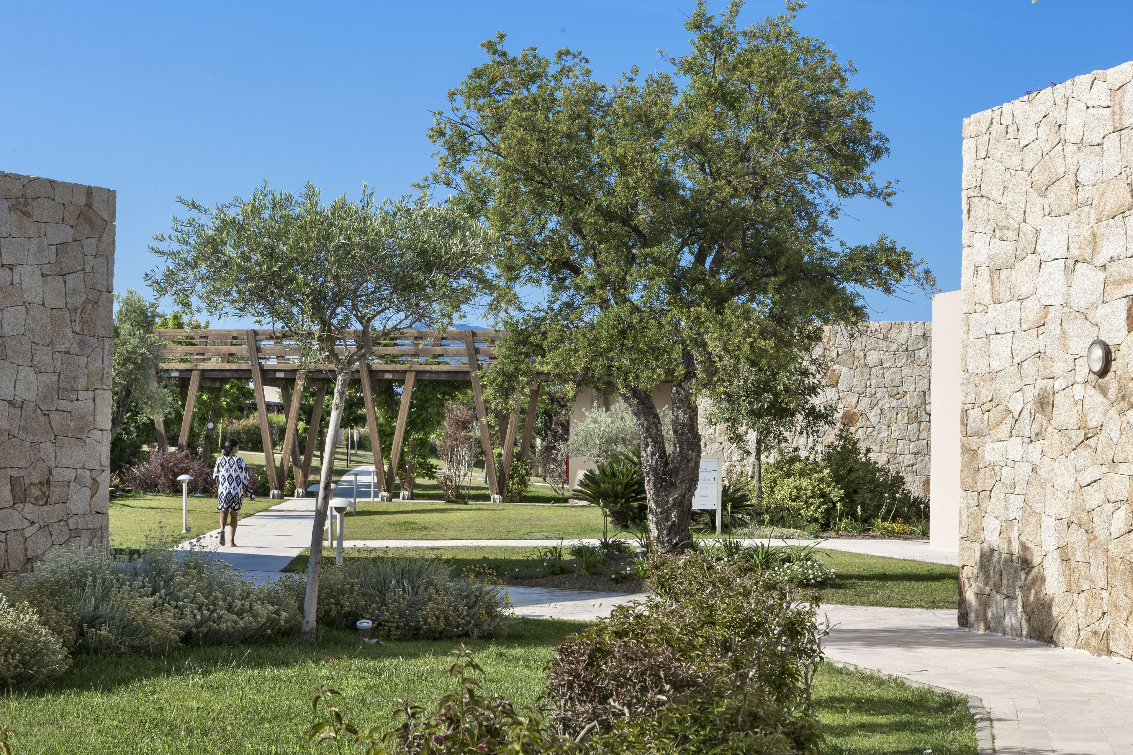 A courtyard with stone walls, a pathway, and greenery.