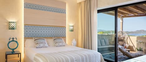 A bedroom with a bed, bedside lamps, a nightstand, a view of the outdoors through a sliding door, and a balcony with a chair.