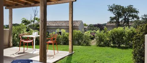 A covered outdoor seating area with two tables, each with a blue towel and a pair of glasses.