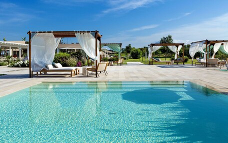 A pool area with clear water, lounge chairs, and canopies.
