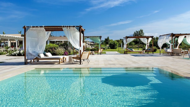 A pool area with clear water, lounge chairs, and canopies. - Baglioni Resort Sardinia - The Leading Hotels of the World (San Teodoro)