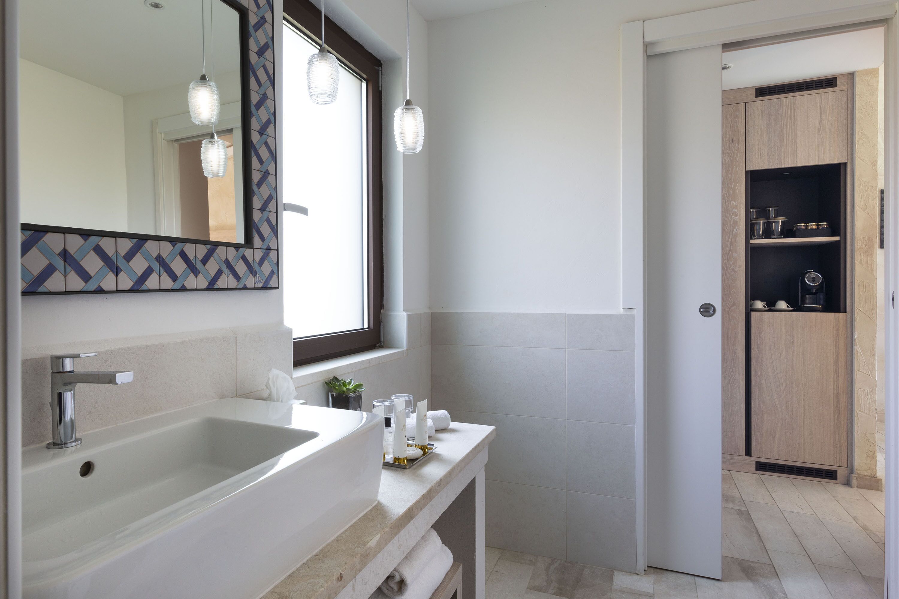 Une salle de bain moderne avec un grand miroir, deux lampes suspendues, un lavabo blanc et un meuble en bois.