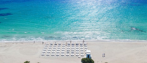 Aan het strand, wit zand, ligstoelen aan het strand, parasols