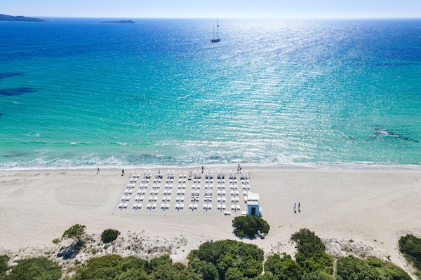 En la playa, arena blanca, sillas reclinables de playa, sombrillas