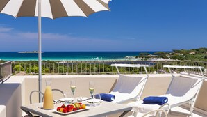 A balcony with a table set for two, a fruit plate, two glasses of white wine, and a pitcher of orange juice. - Baglioni Resort Sardinia - The Leading Hotels of the World (San Teodoro)