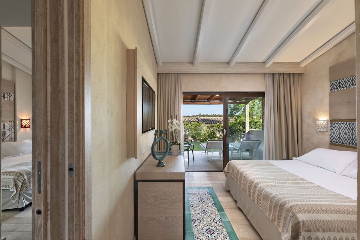 Habitación de hotel con cama, escritorio, silla y vista al exterior.