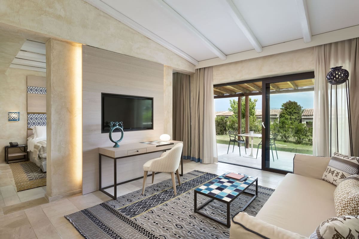 Una sala de estar moderna con una televisión de pantalla plana, un escritorio, una silla blanca, una mesa de centro estampada y un sofá.