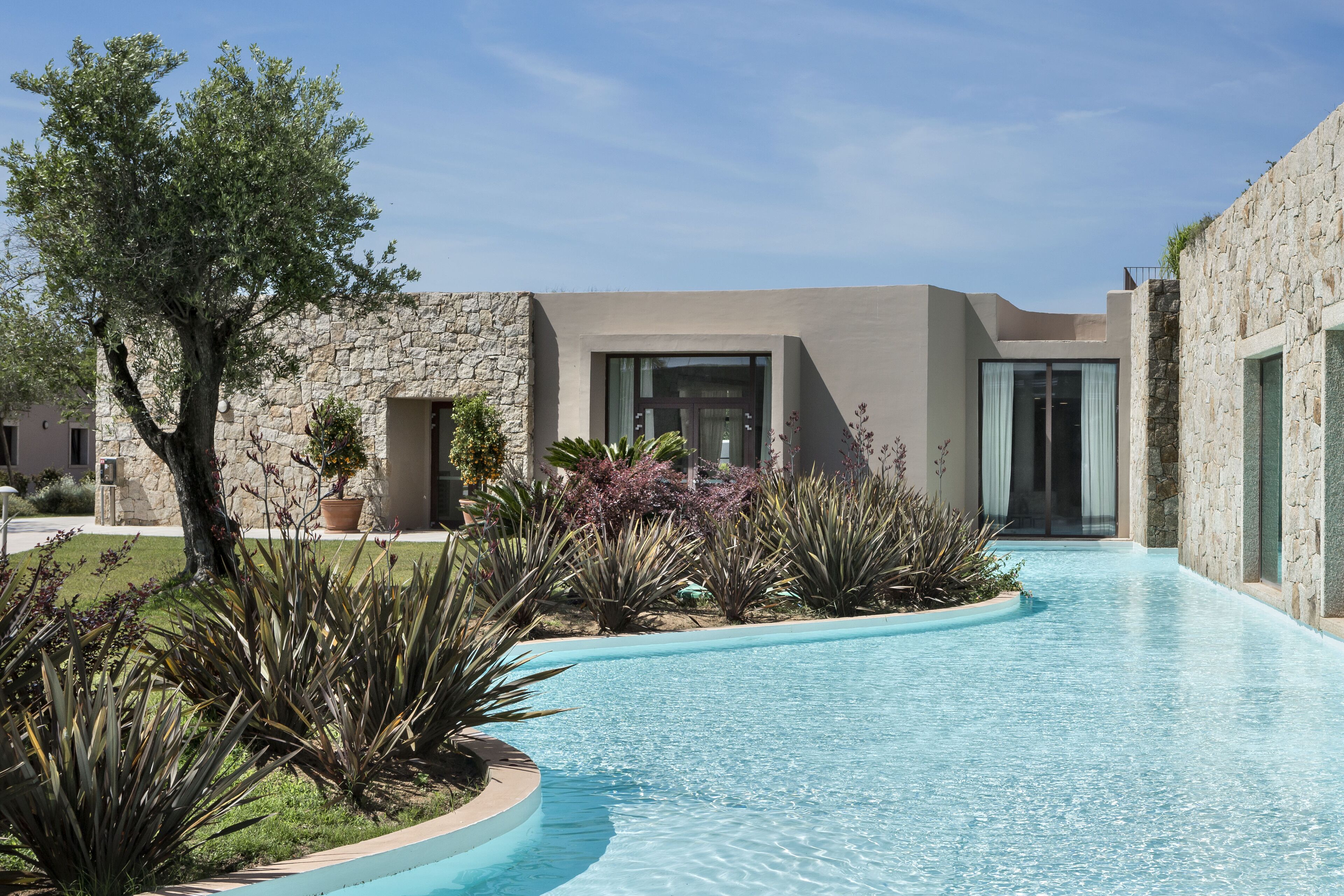 A modern pool area with a stone wall and a glass door entrance.