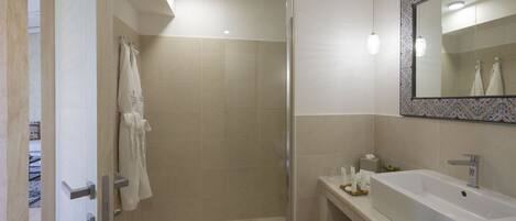 A modern bathroom with a walk-in shower, a large sink, and a mirror with a decorative frame.