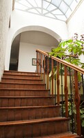 A staircase with wooden steps and black railings, leading to an upper level with a glass ceiling.