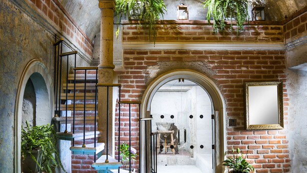 A pool area with a stone ceiling, a chandelier, and potted plants. - La Hostería (Arequipa)