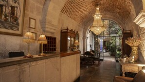 A lobby with a high arched ceiling, a reception desk, and a seating area with a chandelier. - La Hostería (Arequipa)