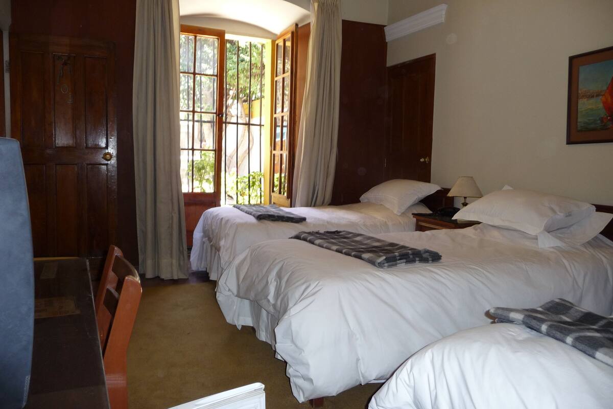 Habitación de hotel con dos camas, un escritorio y una silla.