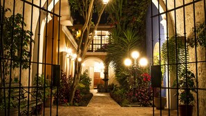 An arched entrance with a brick ceiling, potted plants, and a pathway leading to a building. - La Hostería (Arequipa)