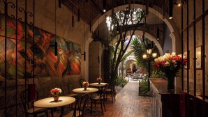 An indoor dining area with brick flooring, wooden tables, chairs, and a mural on the wall. - La Hostería (Arequipa)