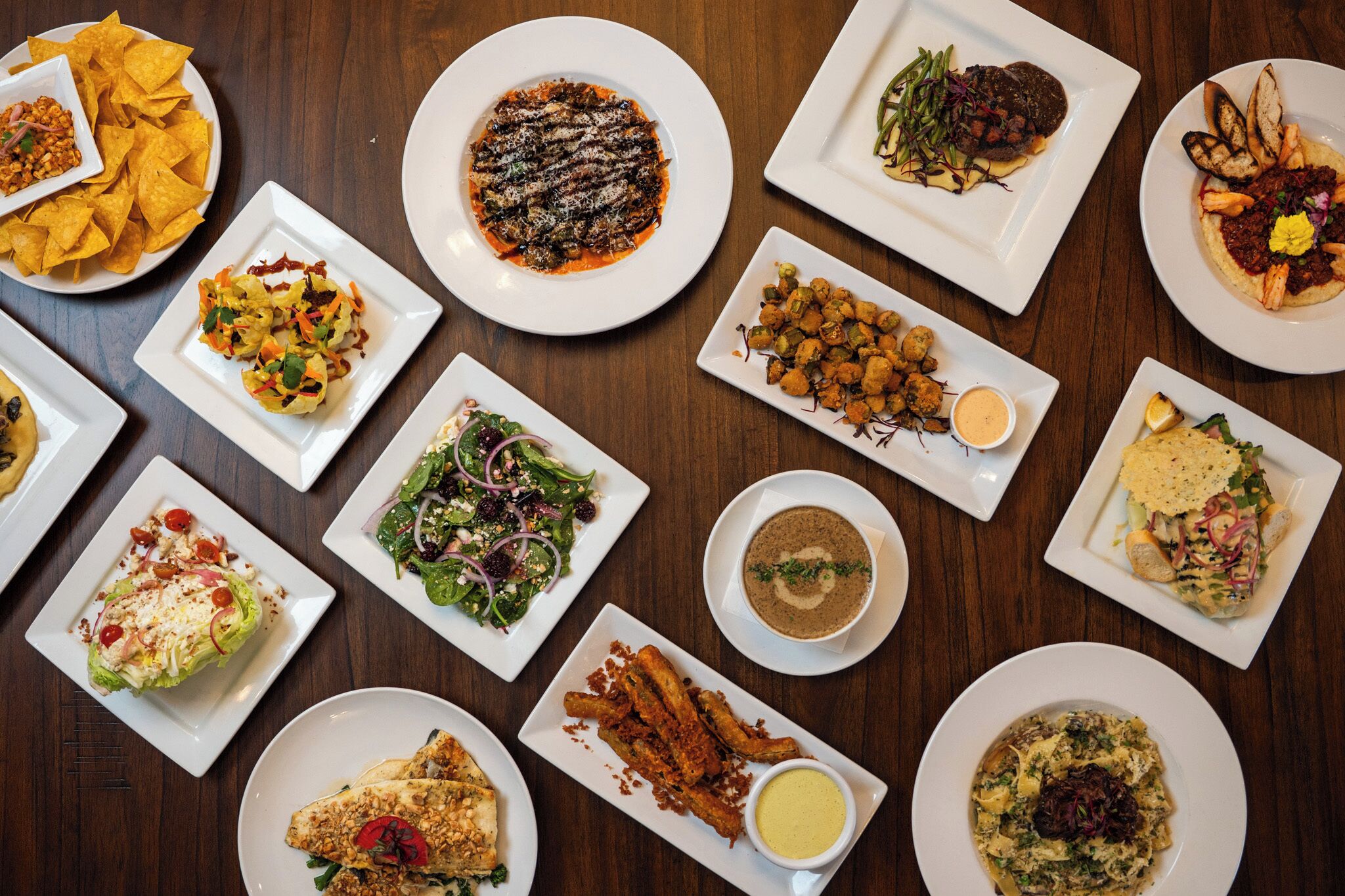 A variety of dishes on white plates arranged on a wooden table.