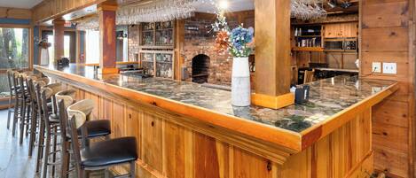 Un espace bar avec des lambris en bois, un comptoir en marbre et des tabourets de bar.