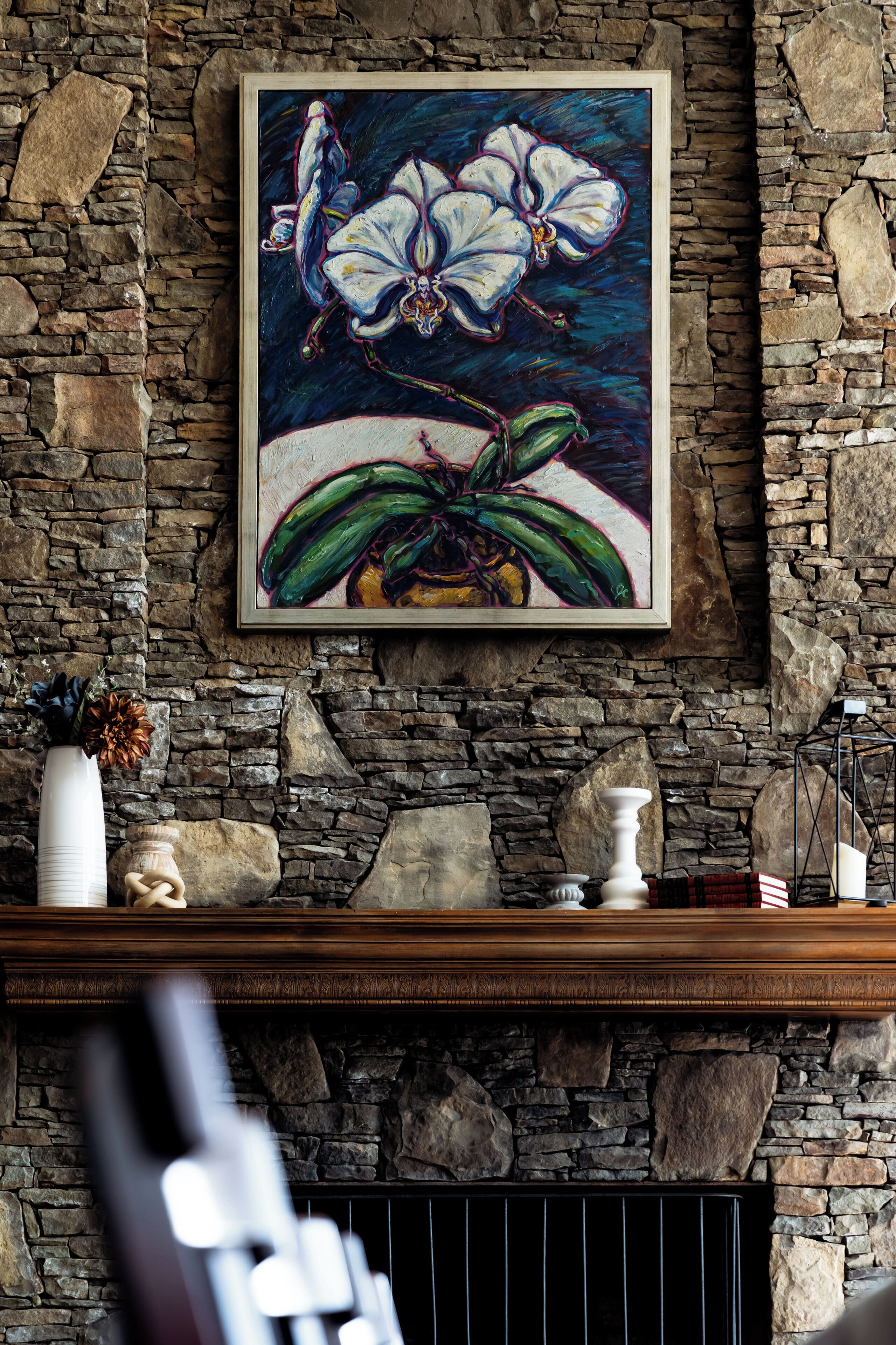 A stone fireplace with a framed painting above it.