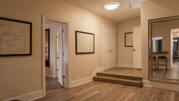 A hallway with wooden flooring, white doors, and framed architectural drawings on the walls.