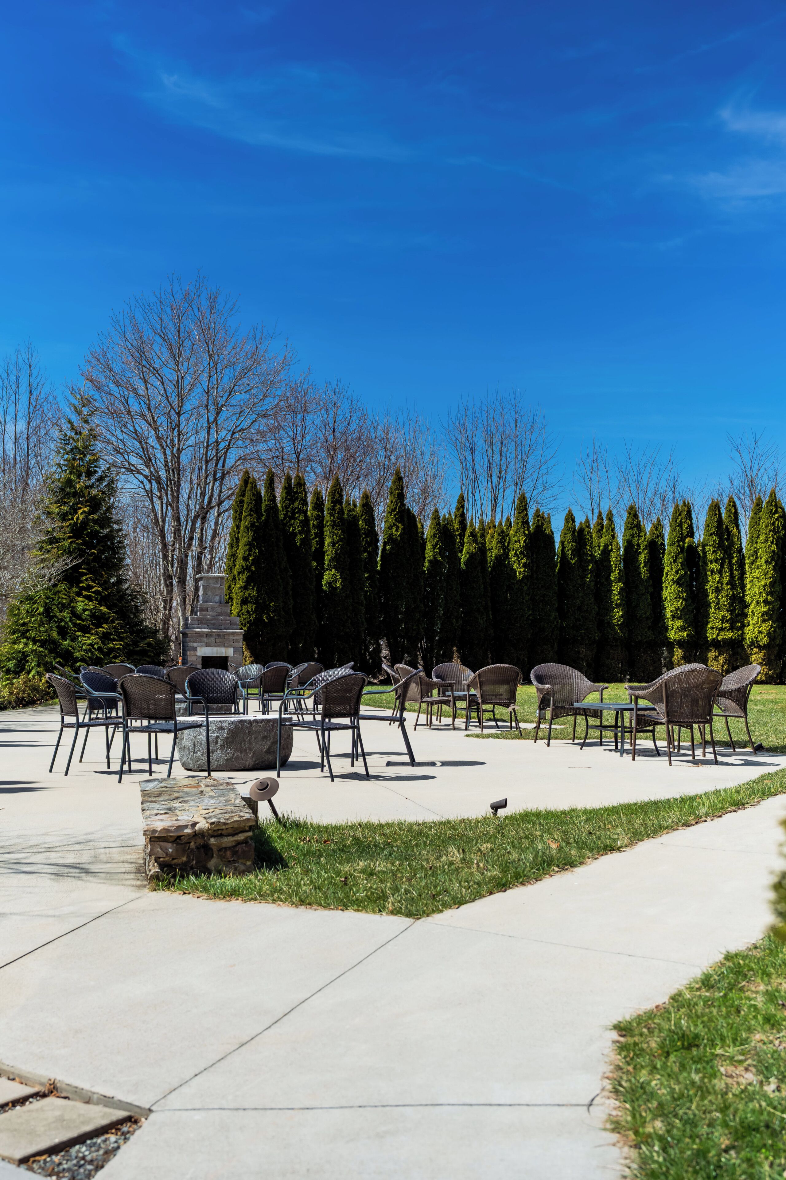 An outdoor patio with chairs and a stone fireplace.