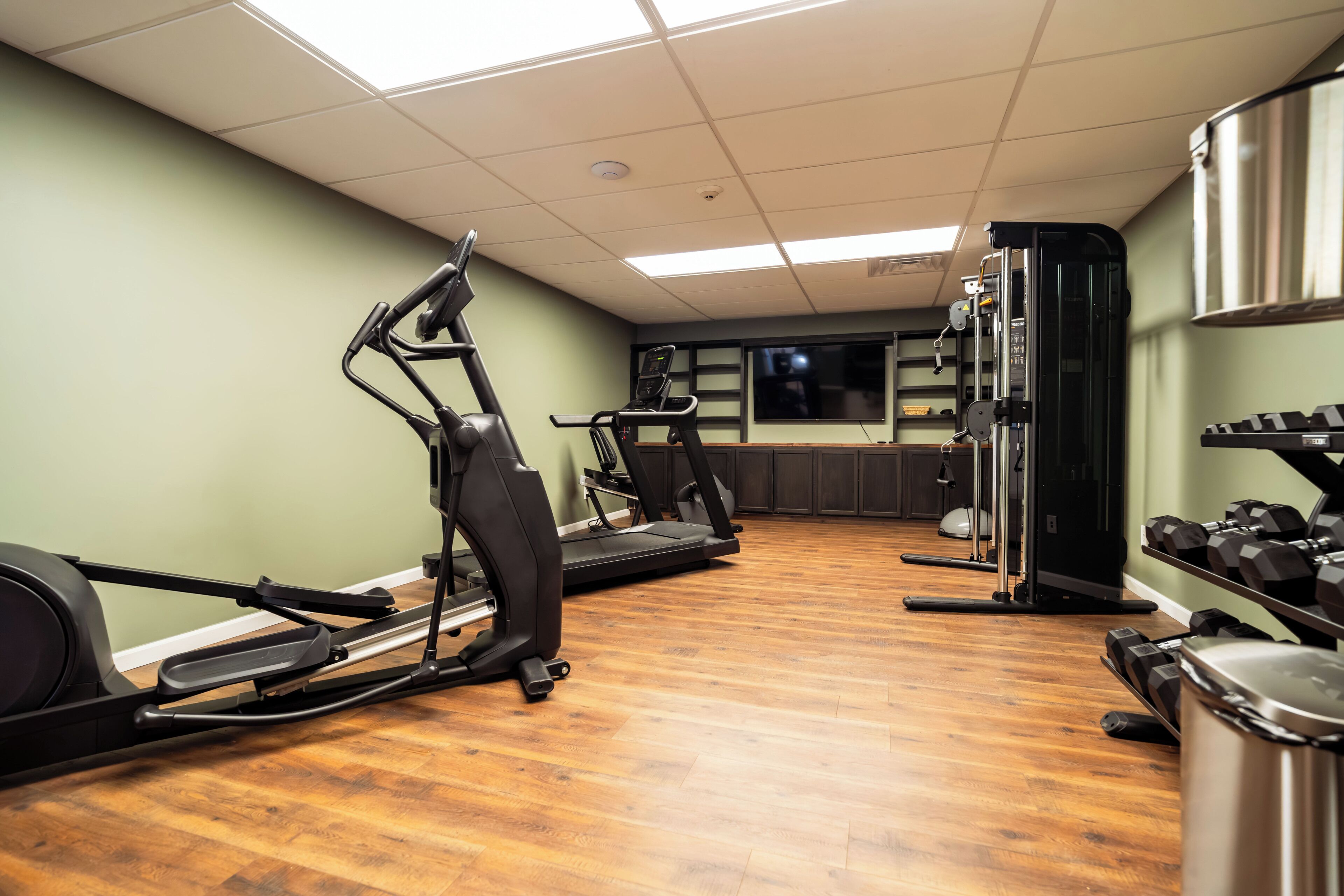 Una palestra con attrezzature da allenamento, pavimento in legno e una finestra.