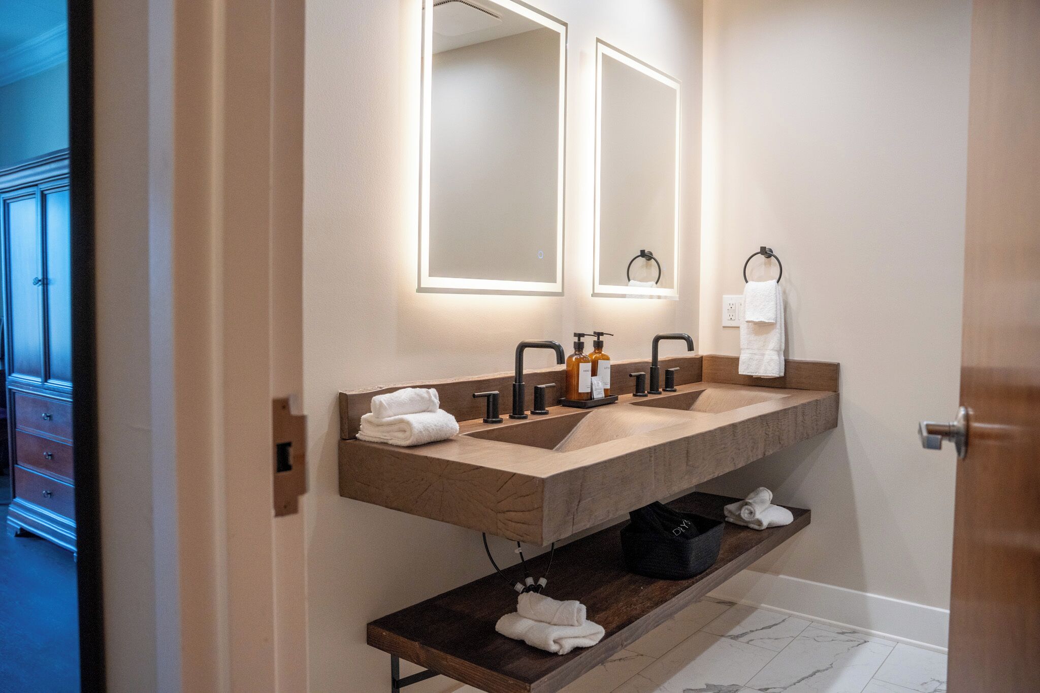 A modern bathroom with a double sink, two mirrors, and a towel rack.