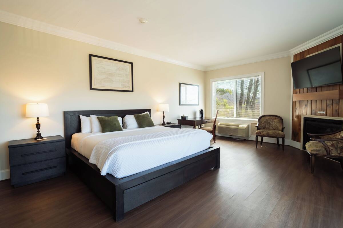 A bedroom with a large bed, bedside tables, a TV, and a window.