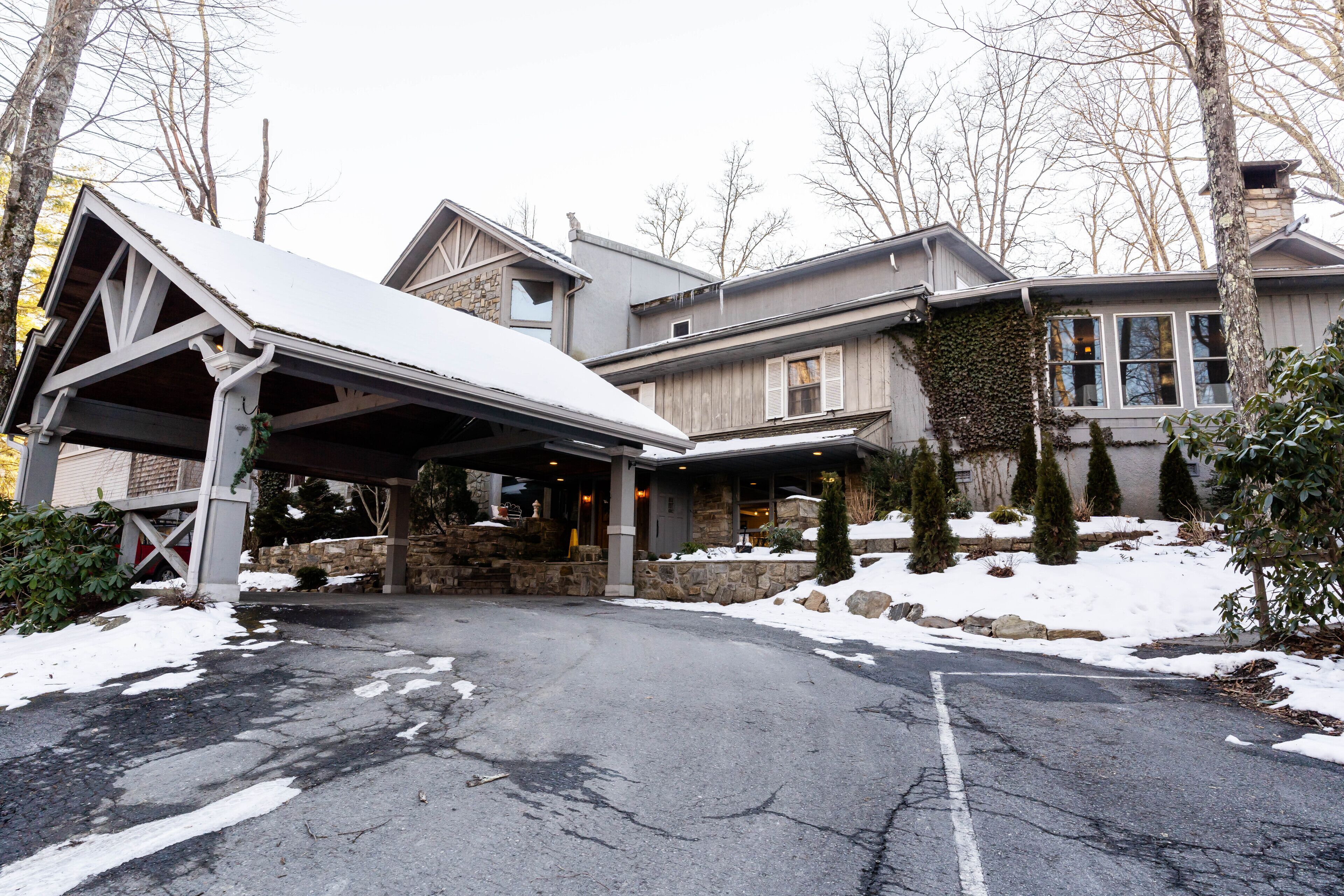 A large, two-story house with a covered driveway and stone foundation.